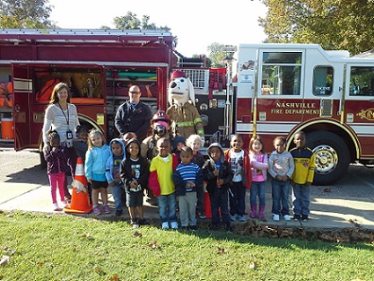 Children and Sparky the Fire dog in front of a fire truck 